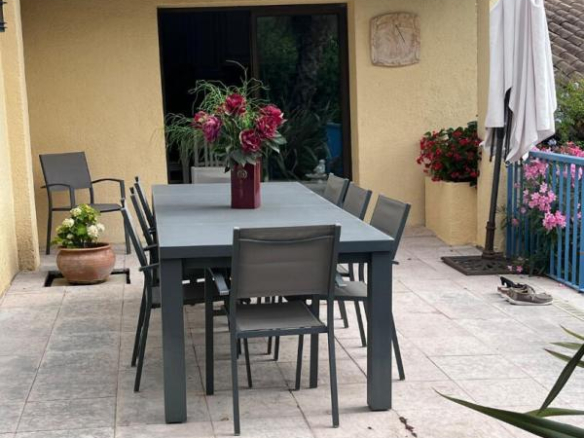 Terrace of a house in Gattières with a large table and chairs, surrounded by plants.