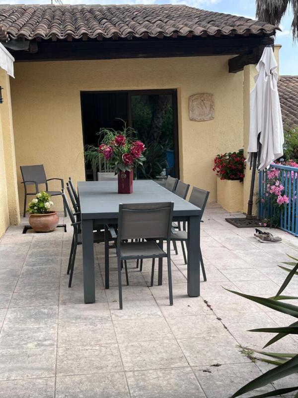 Terrace of a house in Gattières with a large table and chairs, surrounded by plants.