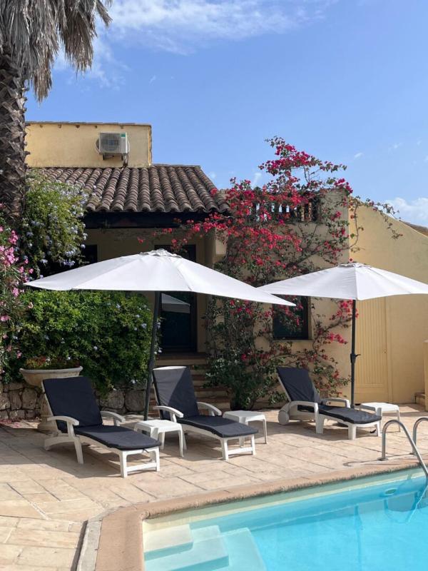 Terrace with sun loungers and parasols near the pool, surrounded by flowers in Gattières.