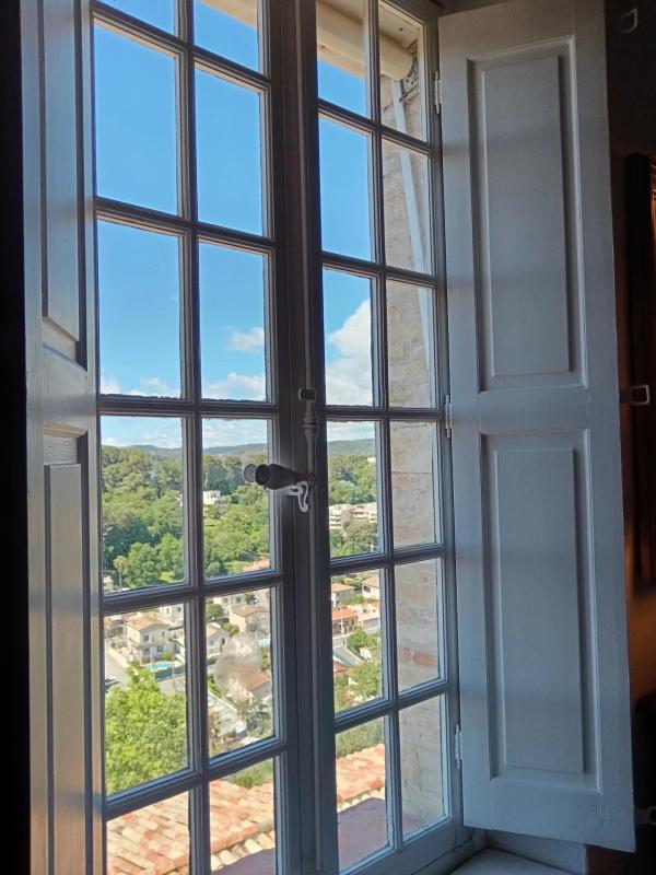 Vue depuis une fenêtre à Cagnes-sur-Mer Vue depuis une fenêtre avec volets ouverts sur des maisons et des arbres en arrière-plan.