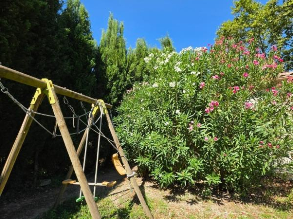 Play area with swing and plants in a quiet garden.