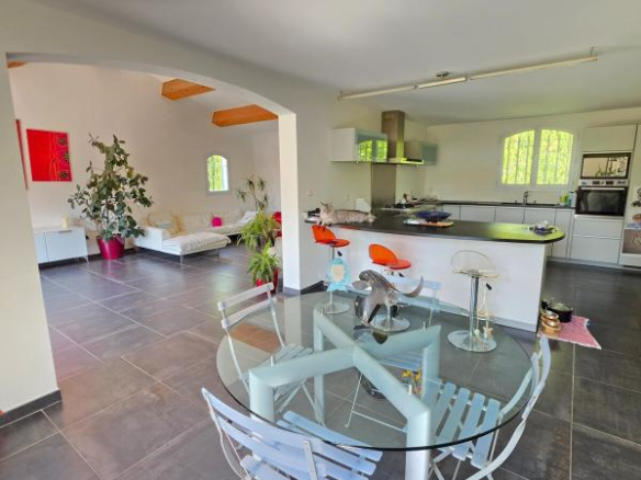 Interior of a modern house with open-plan dining room and kitchen, natural lighting.
