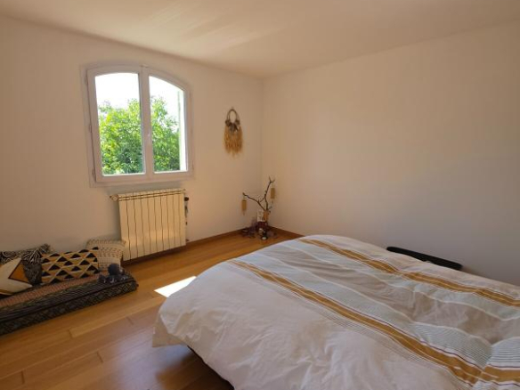 Bright room with bed and window overlooking a garden.