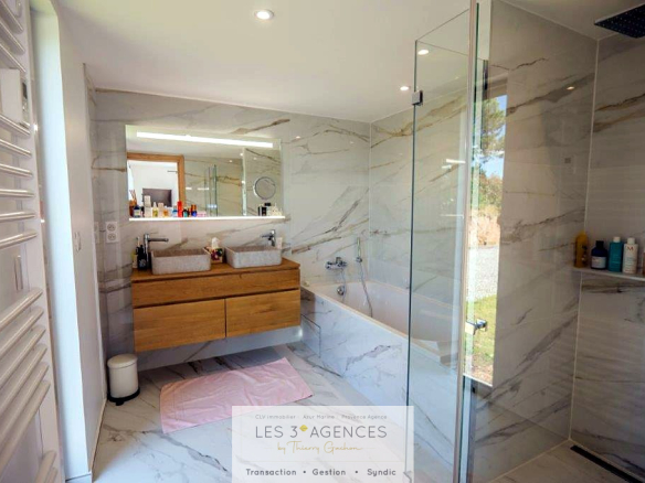Modern bathroom with shower and bathtub, decorated in marble.