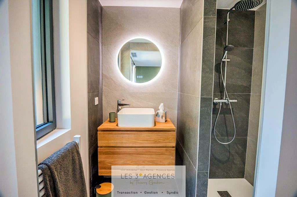 Contemporary bathroom Modern bathroom with shower, washbasin on wooden unit and illuminated round mirror.
