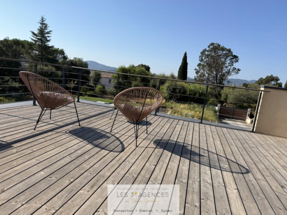 Wooden terrace with chairs in the sun, overlooking nature in Grimaud.