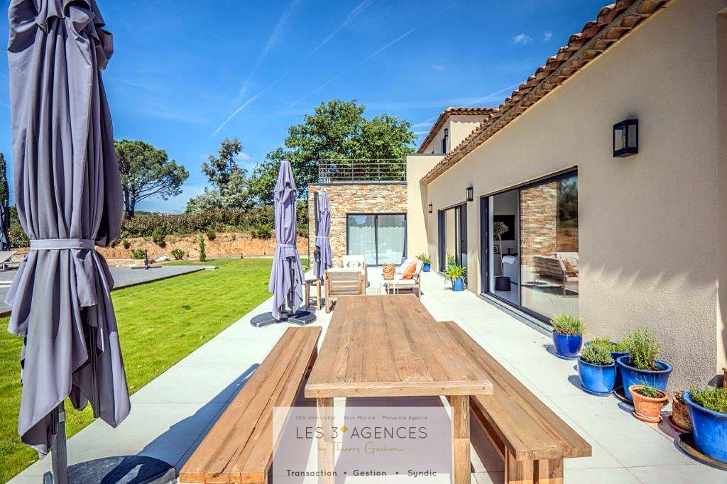 Contemporary villa in Grimaud Terrace of a contemporary villa in Grimaud with wooden table and parasols, garden view.
