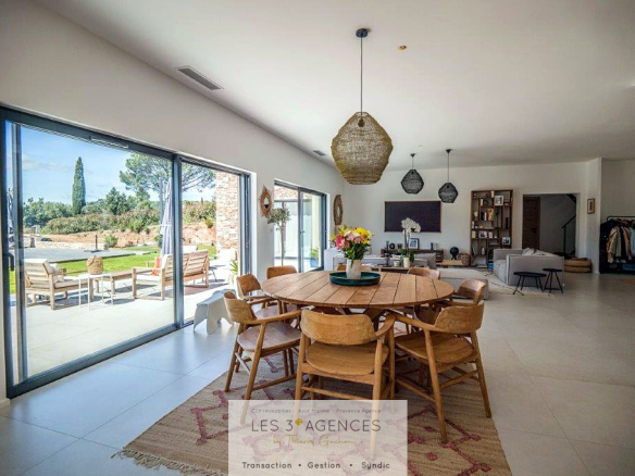 Interior of a contemporary villa for sale in Grimaud, bright dining room with garden view.