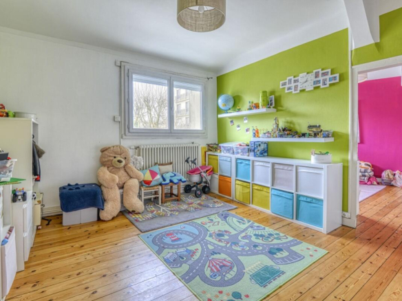 Spacious children's room with green walls and toys, wooden parquet floor.