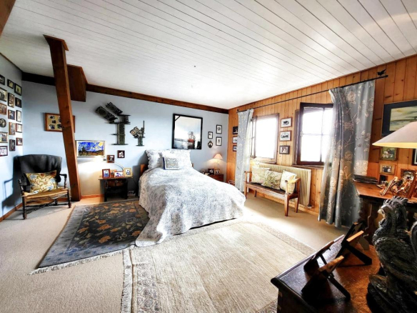 Spacious room in a traditional chalet in Grilly, with wooden walls and wall decorations.