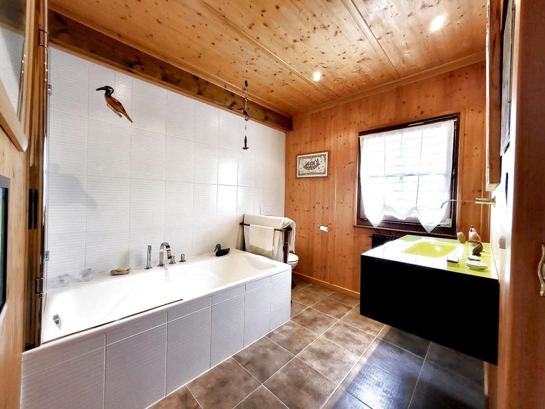 Bathroom in the chalet in Grilly Bathroom in a traditional chalet with bathtub and wooden washbasin unit.