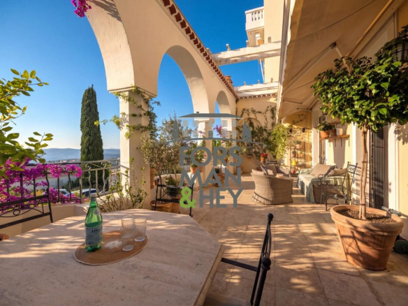 Terrace of an apartment in Grasse with sea view, plants and garden furniture.