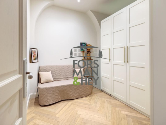 Interior of a renovated apartment with a sofa and white cupboards.