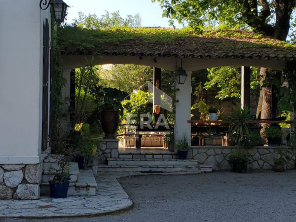 Entrance to a 1960s house with a covered terrace and a green garden in La Gaude.