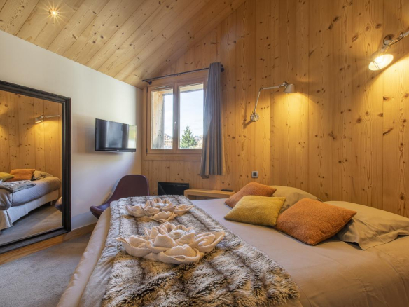 Chambre d'un chalet en bois avec lit, miroir et télévision.