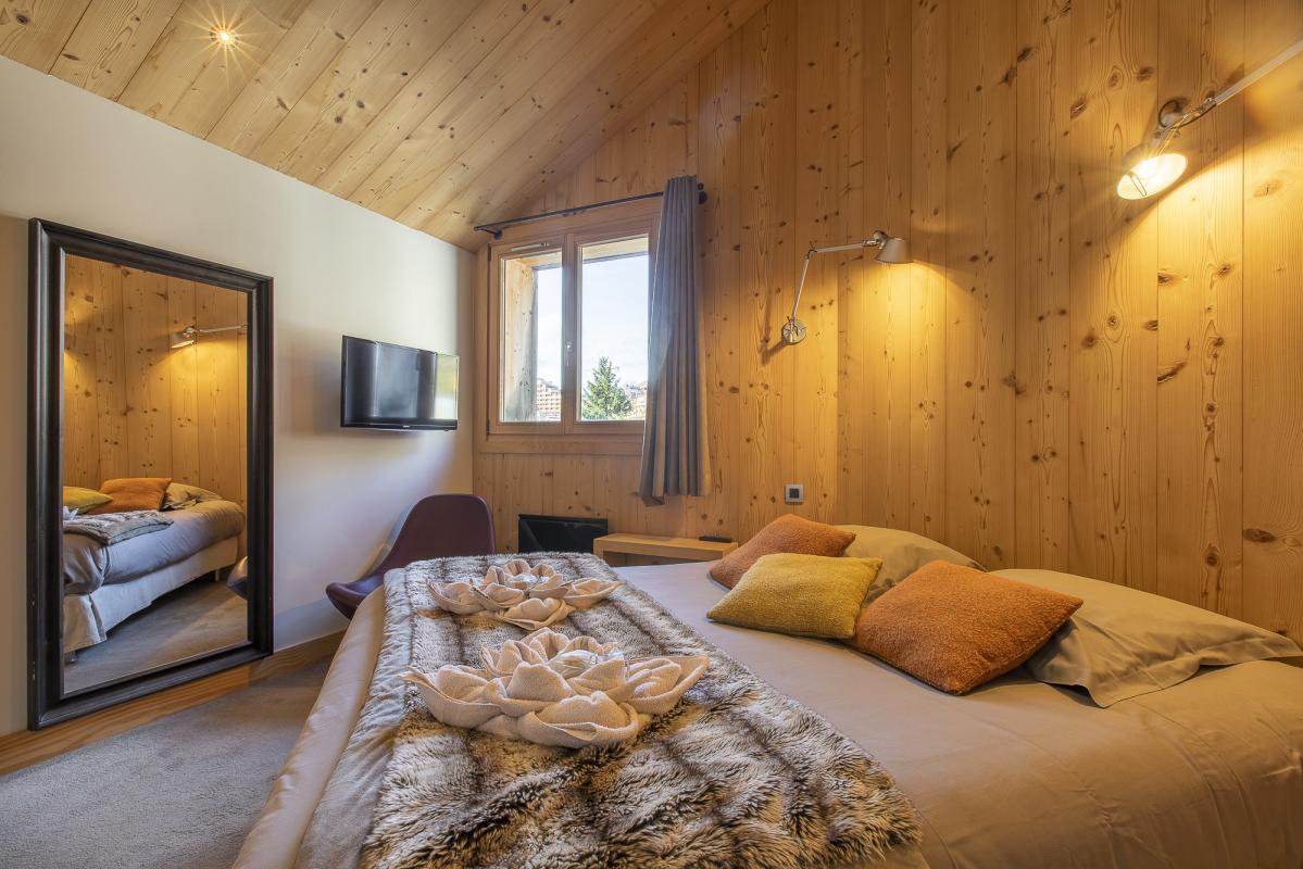 Chambre du Chalet ALAYA NOA Chambre d'un chalet en bois avec lit, miroir et télévision.