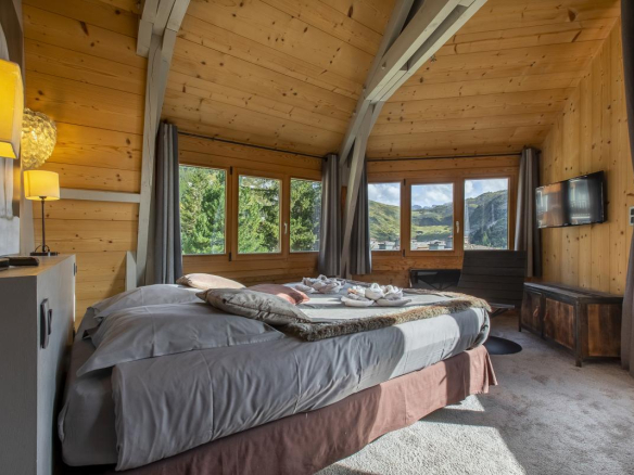 Chambre d'un chalet avec lit double, fenêtres panoramiques et décoration en bois à Avoriaz.