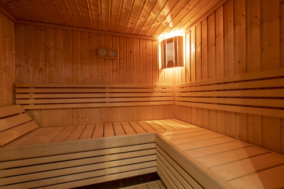 Intérieur du sauna du Chalet ALAYA NOA Intérieur d'un sauna en bois avec bancs en bois et éclairage doux.