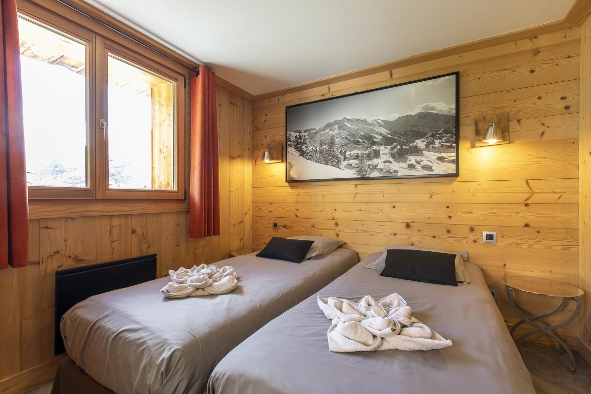 Chambre du Chalet ALAYA NOA Chambre avec deux lits simples et murs en bois, fenêtre laissant entrer la lumière.