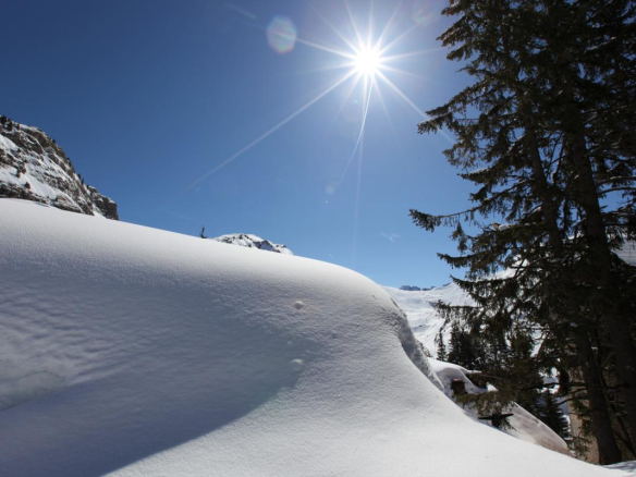 Paysage enneigé avec des montagnes et un ciel bleu à Avoriaz, soleil brillant.