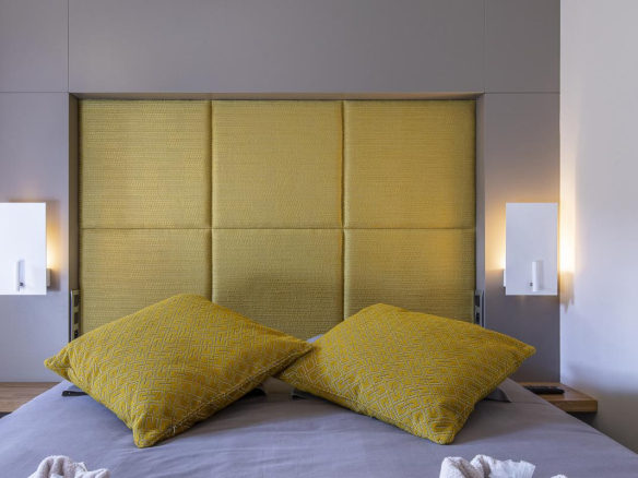 Chambre avec lit double et coussins jaunes dans un chalet contemporain.
