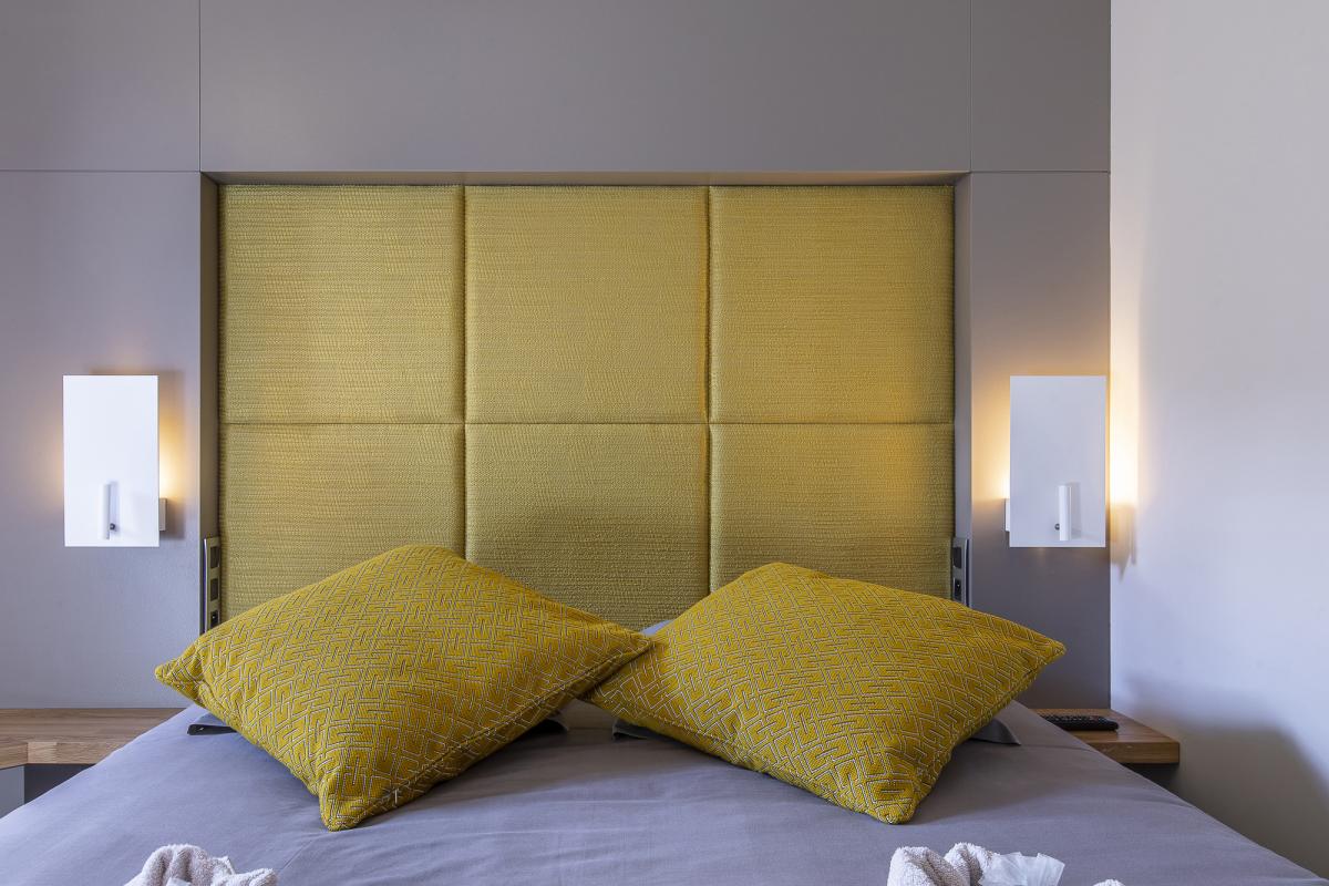 Chambre du Chalet ALAYA ALBA Chambre avec lit double et coussins jaunes dans un chalet contemporain.