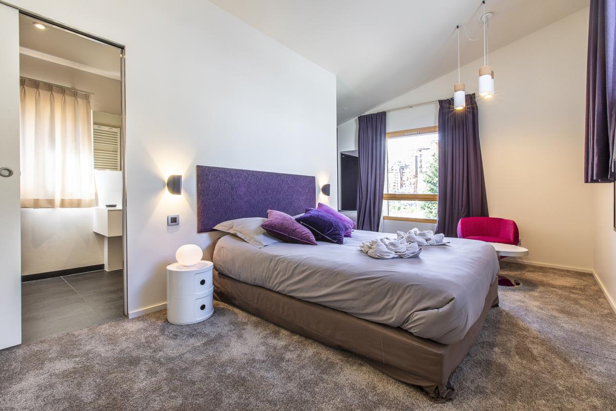 Chambre du Chalet Alaya Alba Chambre d'un chalet moderne avec lit, fauteuil et salle de bain attenante.