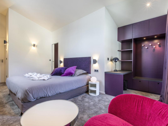 Chambre moderne avec lit double, fauteuils et bureau dans un chalet à Morzine.
