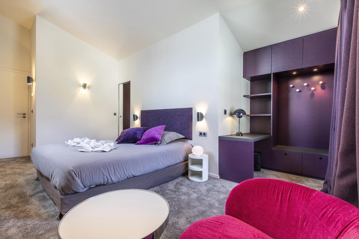 Chambre du Chalet ALAYA ALBA Chambre moderne avec lit double, fauteuils et bureau dans un chalet à Morzine.