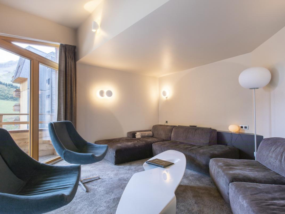 Intérieur d'un chalet moderne avec un salon confortable, canapé et vue sur la montagne.