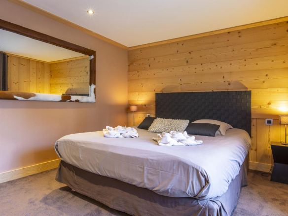 Chambre d'un chalet avec lit double, murs en bois et décoration contemporaine.