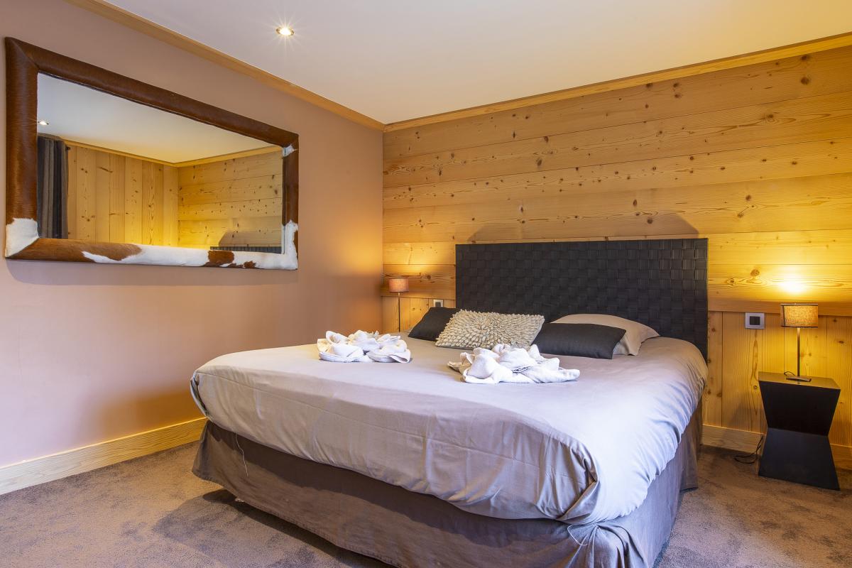 Chambre du Chalet ALAYA ALBA Chambre d'un chalet avec lit double, murs en bois et décoration contemporaine.