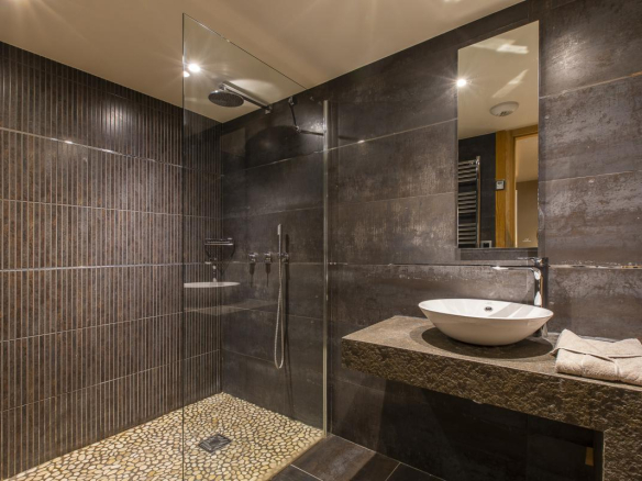 Salle de bain moderne avec douche en verre et lavabo design dans un chalet.