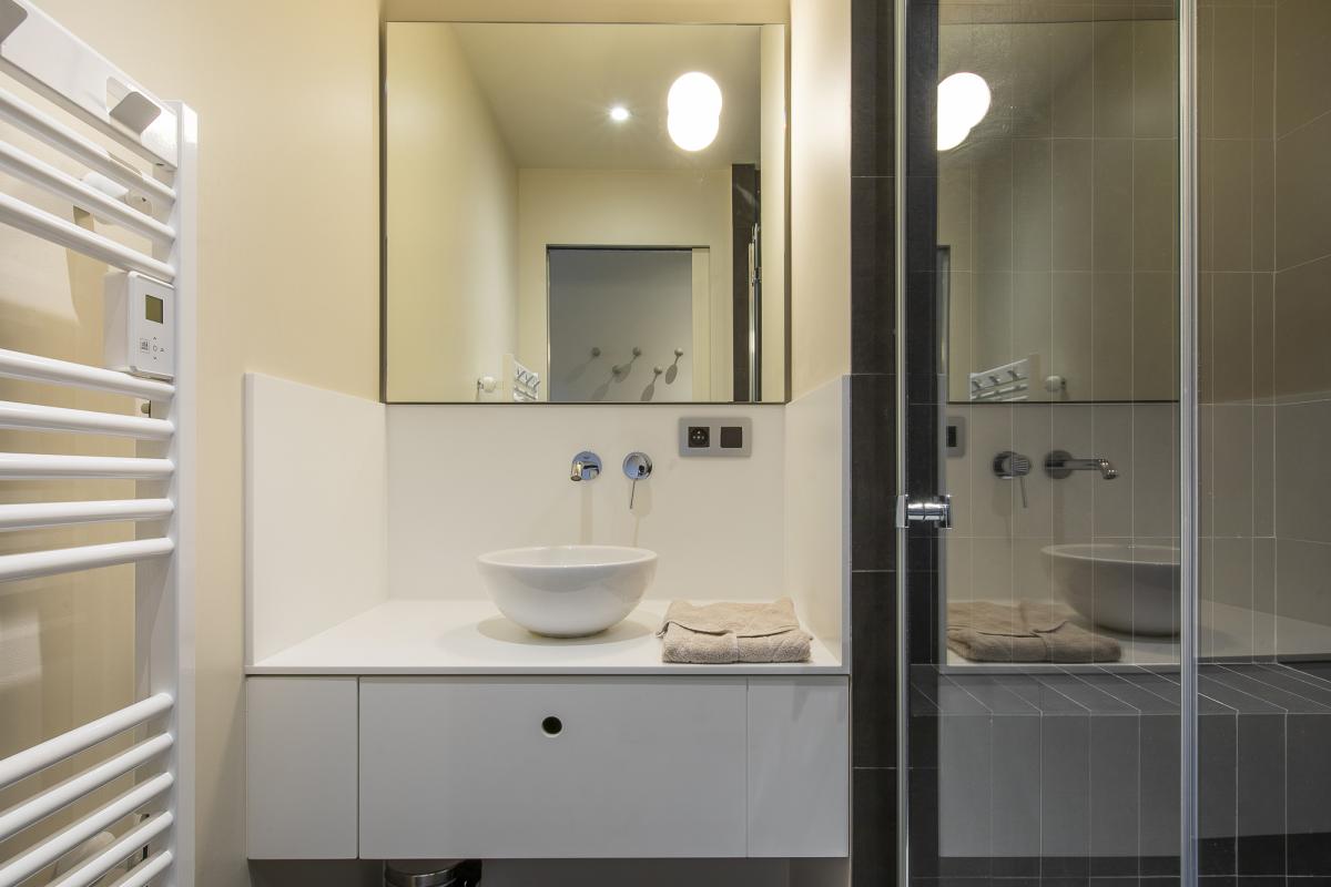 Salle de bain du Chalet ALAYA ALBA Salle de bain moderne avec douche, lavabo et miroir, dans un chalet à Morzine.