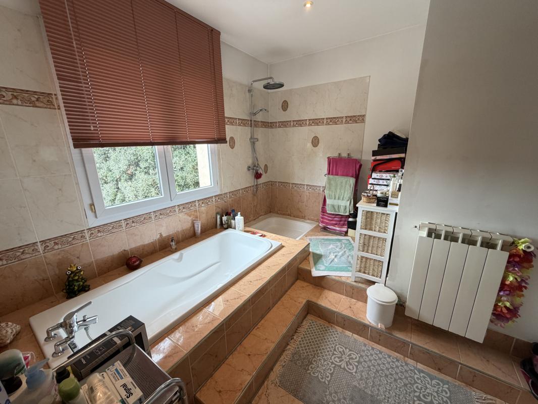 Salle de bain spacieuse Salle de bain spacieuse avec baignoire et douche, décorée en carrelage beige.