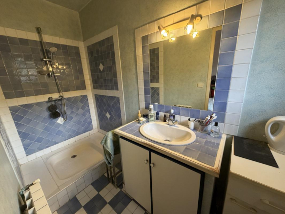 Salle de bain avec baignoire et douche, carrelage bleu et blanc.