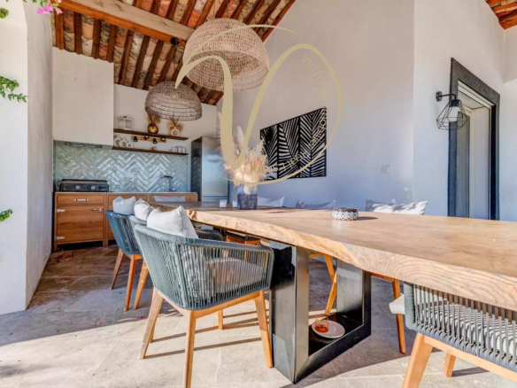 Interior of a contemporary villa with a large wooden table and chairs, open kitchen.