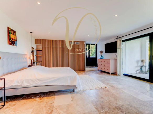 Modern room with bed, parquet flooring and access to the outside in a contemporary villa.