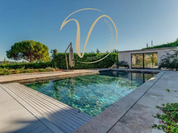 Heated swimming pool of a contemporary villa in La Colle-sur-Loup, with views of the hills and the sea.