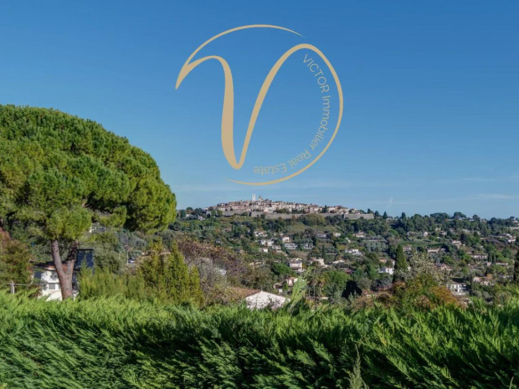 View of the villa of Saint Paul de Vence from La Colle-sur-Loup, with hills and trees in the foreground.
