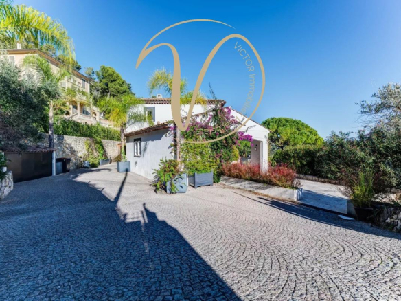 Entrance to a contemporary villa with paved driveway, vegetation and unobstructed views of the hills.