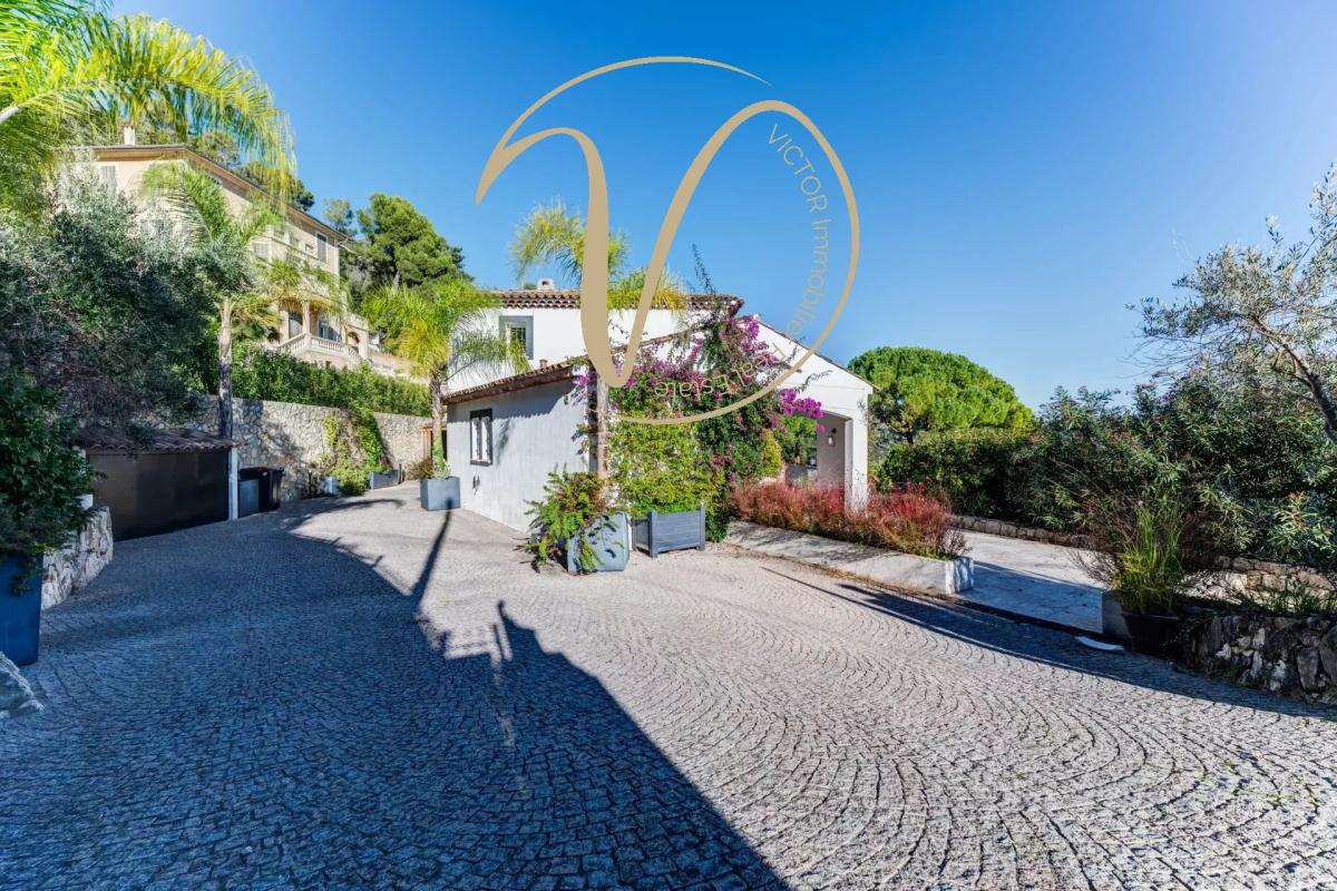 Entrance to a contemporary villa in La Colle-sur-Loup Entrance to a contemporary villa with paved driveway, vegetation and unobstructed views of the hills.