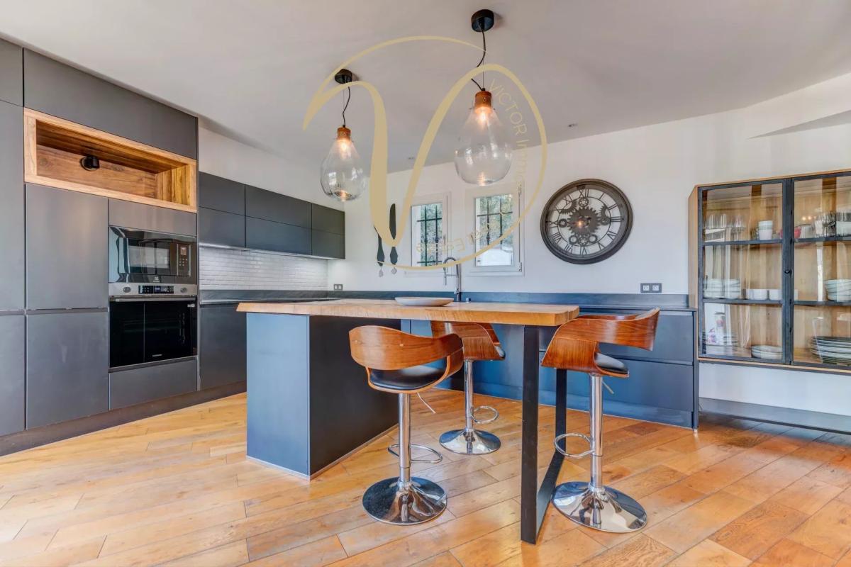 Contemporary kitchen with central island Modern kitchen with central island and bar, pendant lighting, and wood and black furniture.