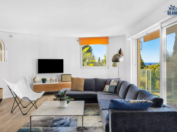 Intérieur d'une villa à Cannes avec un salon moderne, canapé, télévision et vue sur le jardin.