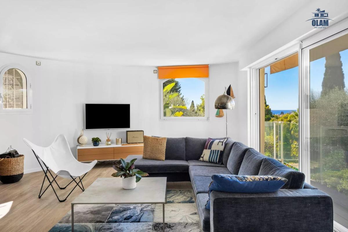 Intérieur d'une villa à Cannes avec un salon moderne, canapé, télévision et vue sur le jardin.