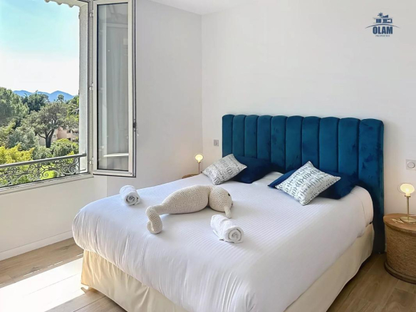 Chambre d'une villa à Cannes avec vue sur la nature, lit double et décoration moderne.