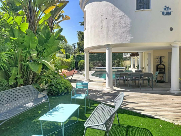 Terrasse d'une villa à Cannes avec mobilier moderne, piscine et jardin luxuriant.