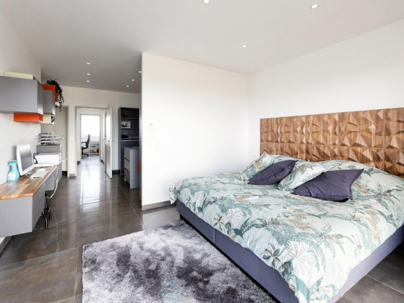 Chambre d'une villa contemporaine avec lit double et coin bureau.