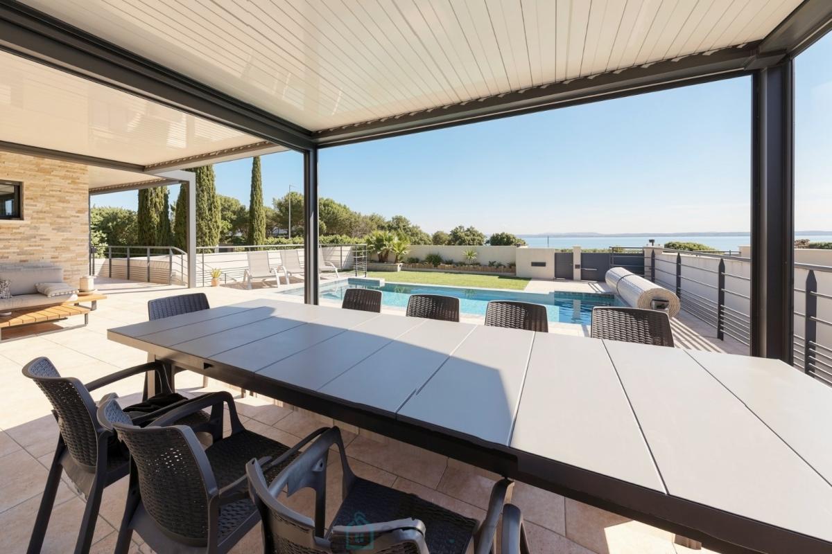 Terrasse de villa contemporaine à Istres Terrasse d'une villa contemporaine avec piscine, chaises et vue dégagée sur la nature.