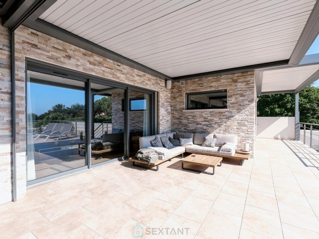 Terrasse de villa contemporaine à Istres Terrasse d'une villa contemporaine avec mobilier en bois et vue dégagée.
